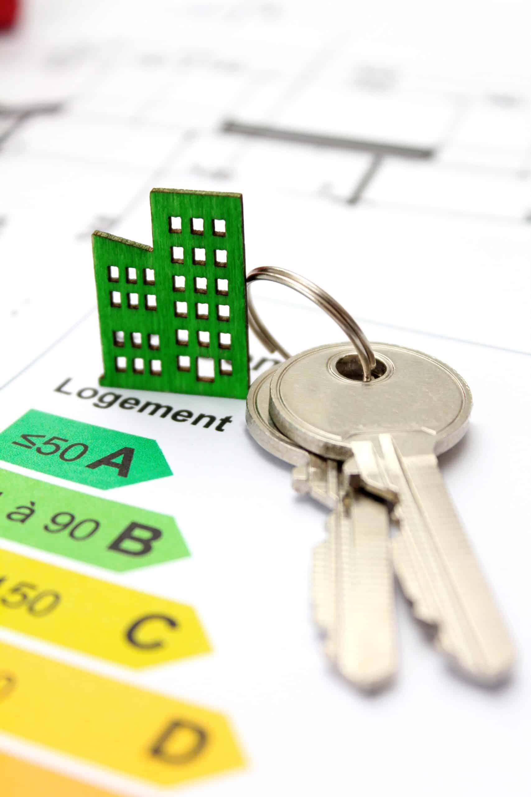 Clés et maquette d'immeuble vert sur diagnostic de performance énergétique affichant la note A <50.