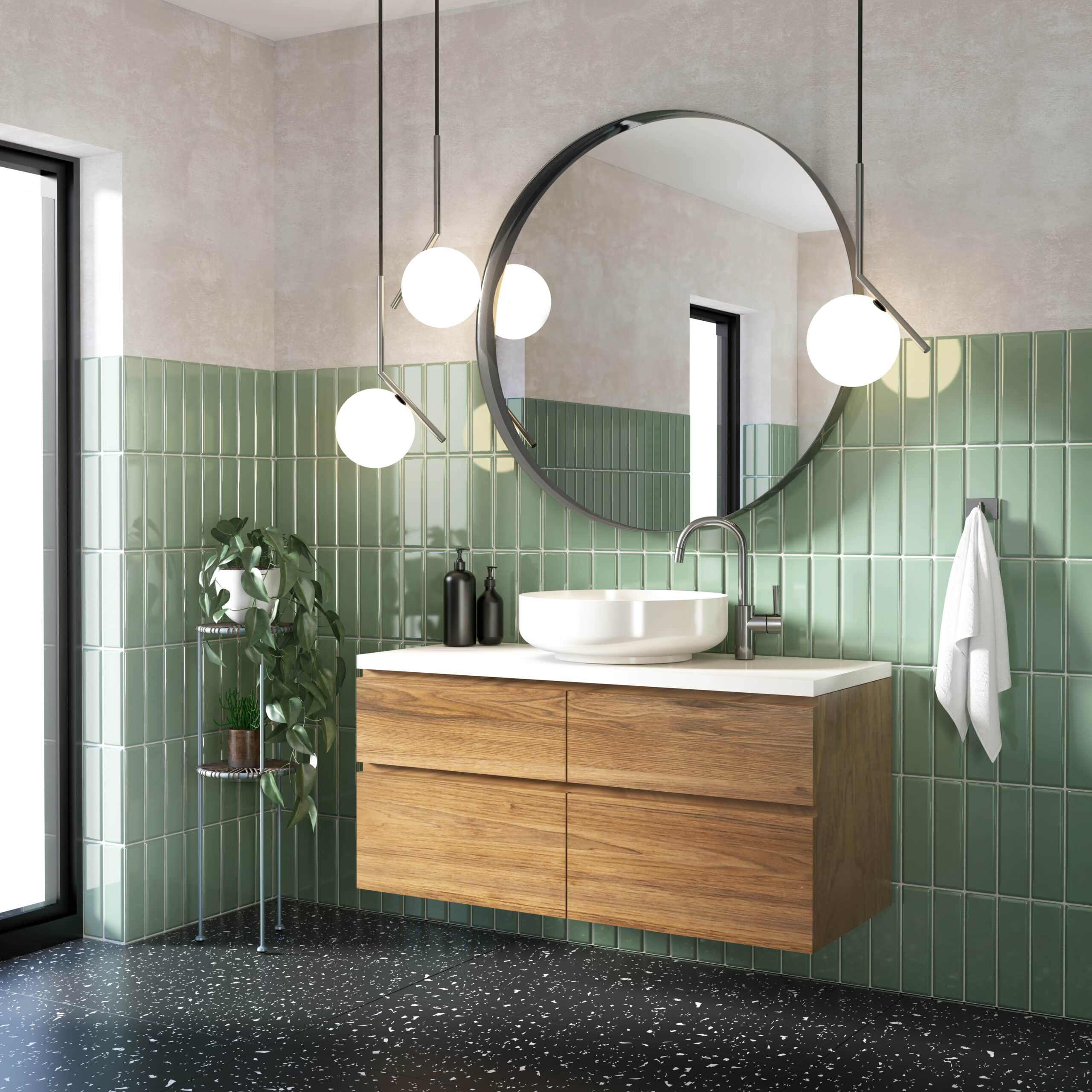 Salle de bain moderne avec mur carrelé vert sauge, meuble-lavabo flottant en bois, vasque blanche, miroir rond, et éclairage suspendu.
